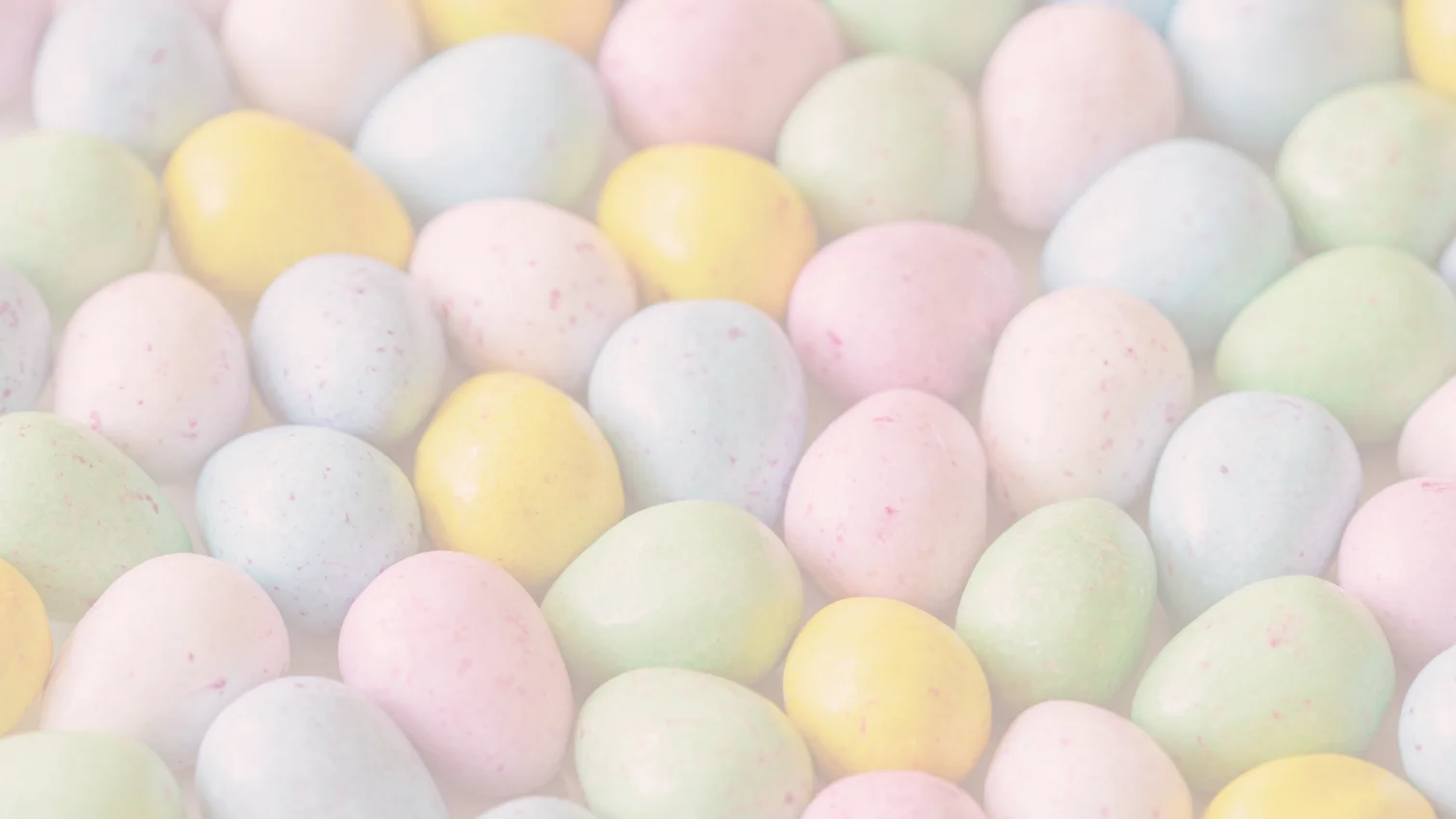 På på pastellfärgade påskäggsgodisar, förmodligen choklad. i grönt, gult, blått och rosa 