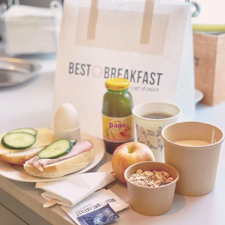 En frukostpåse från Hotel Svava. På bilden syns vår to-go frukost: en stor fralla, juice, frukt, youghurt, müsli, ägg och kaffe eller te.