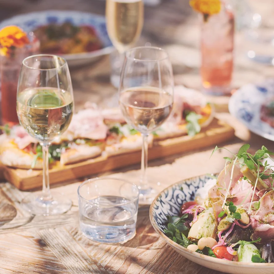 Burnch serverad på ett somrigt uppdukat bord med Italienska delikatesser och drinkar prydda med blommor